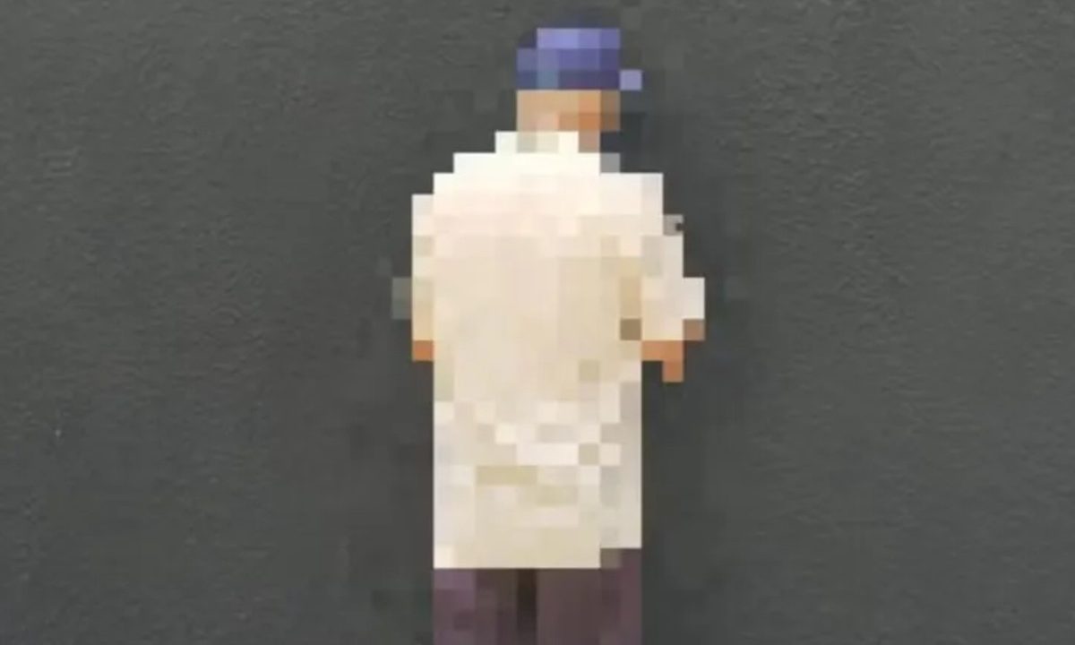 Foto mostra homem preso em flagrante por abaixar as calças e importunar sexualmente adolescente no Paraná. Ele está de costas e usa camisa branca, boné azul e calça marrom