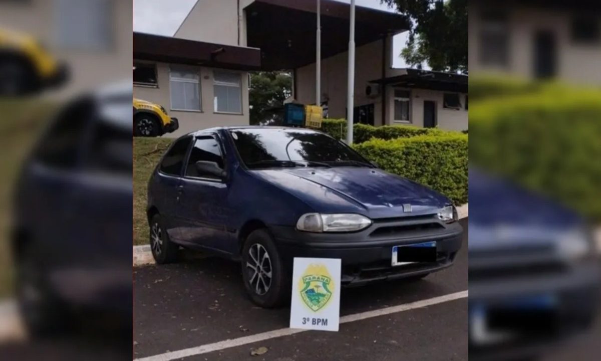 Fiat Palio azul-marinho estacionado em frente a uma delegacia no Paraná no caso do homem preso após vender o próprio carro e fingir furto do veículo.