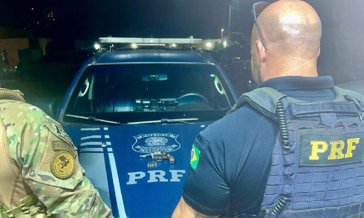 Foto mostra agentes da PRF com arma utilizada pelos suspeitos de sequestrar homem