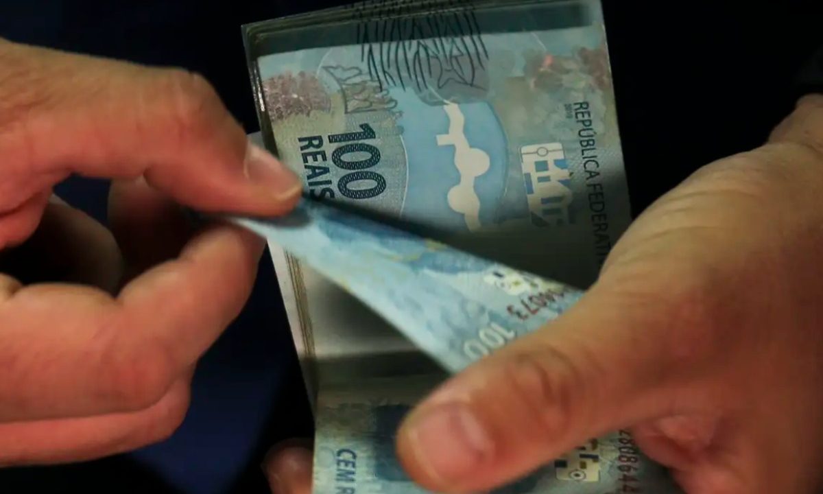 Foto de mão contando cédulas de R$ 100; dinheiro usado para ilustrar o valor que será recebido pelo ganhador da Lotofácil 3644