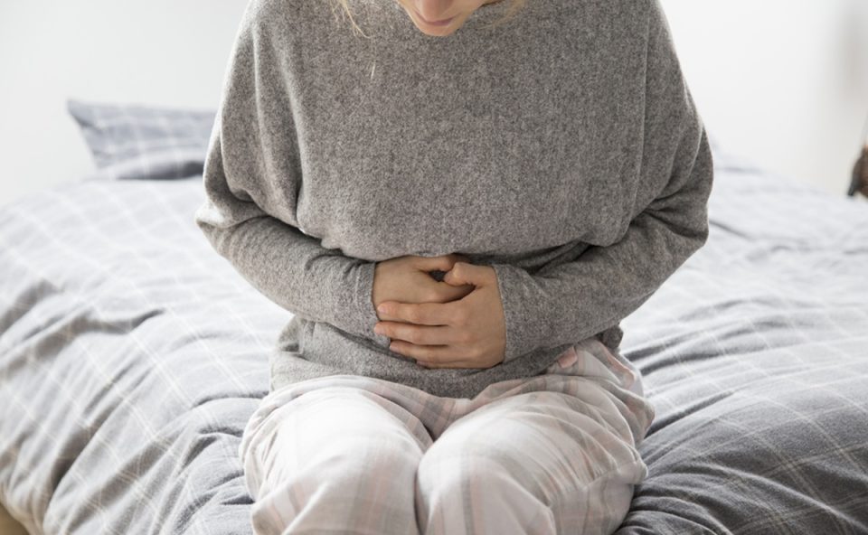 Mulher com dor abdominal representando casos de câncer de intestino, que devem ter número de mortes triplicadas no Brasil