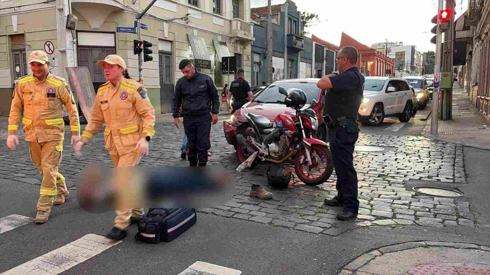 Motociclista atingido pelo carro em Curitiba caido no chão e recebendo atendimento