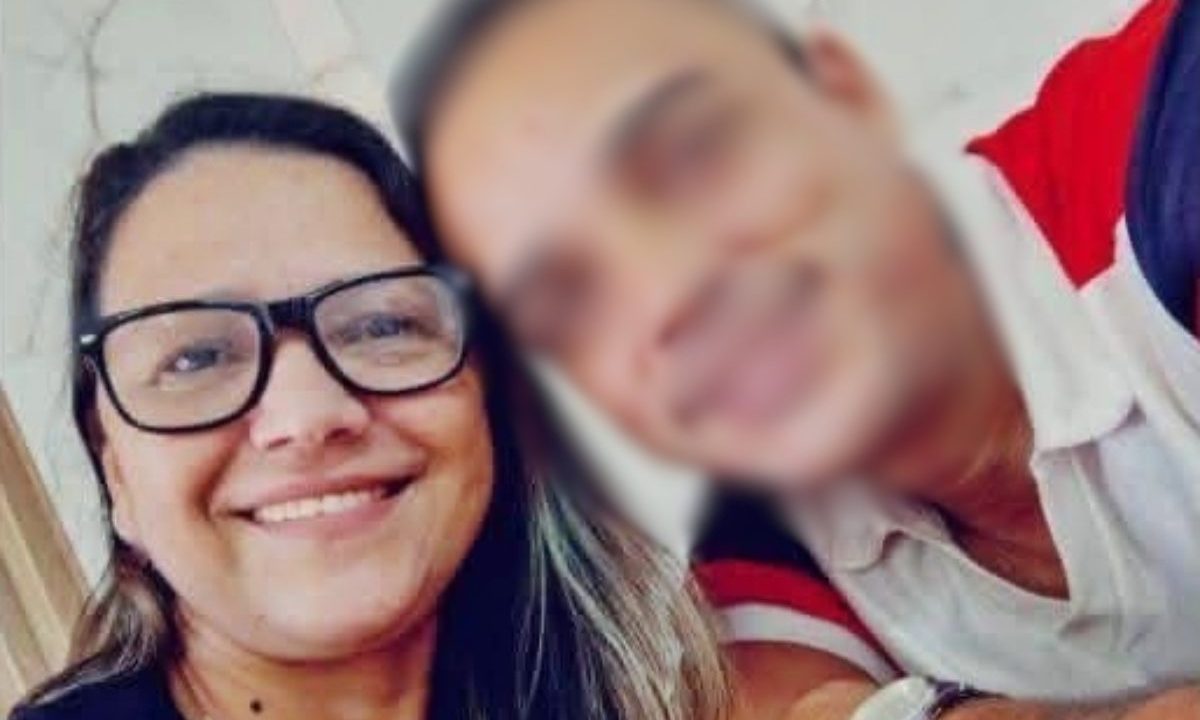 Imagem mostra a mulher encontrada morta no sofá ao lado do suspeito pelo crime. Os dois eram um casal. Ela usa óculos e está com cabelo soltos e camiseta preta, sorrindo para foto. O suspeito está com rosto borrado. Ele é branco, usa camiseta branca, vermelha e preta.