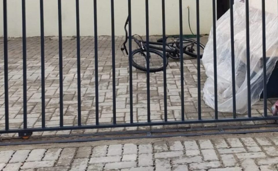 Mulher que sofreu tentativa de feminicídio no Dia Internacional da Mulher tinha medida protetiva e vive escondida. Imagem mostra um portão e uma bicicleta caída.