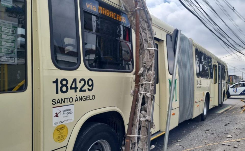 Ônibus articulado do transporte coletivo parado após colidir contra um poste danificado no bairro Bacacheri, em Curitiba.