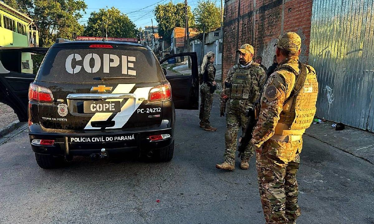 Foto mostra agentes do COPE parados ao lado de viatura durante operação