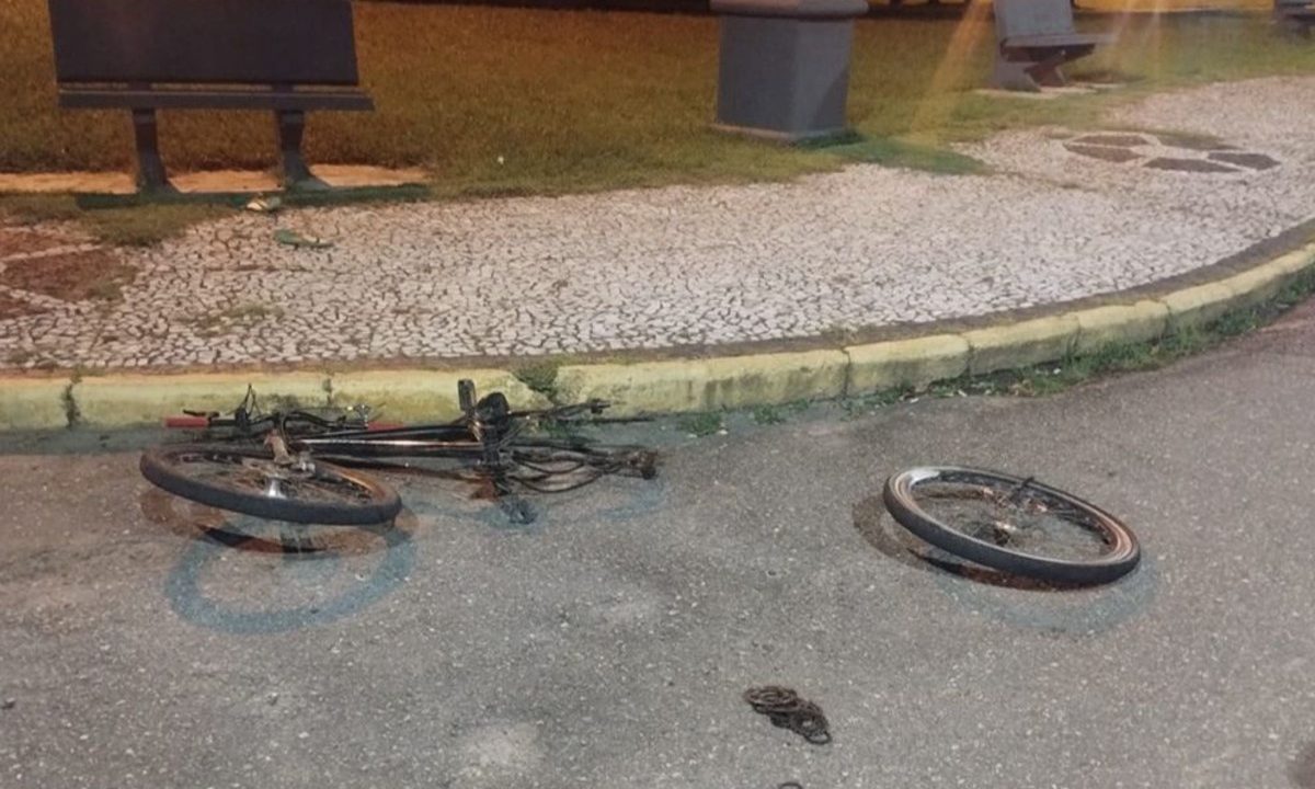 Foto mostra bicicleta sem um pneu, caída no asfalto. O pneu foi quebrado e está afastado da bicicleta. Pai jogou carro contra filho e ex. Depois sequestrou as crianças