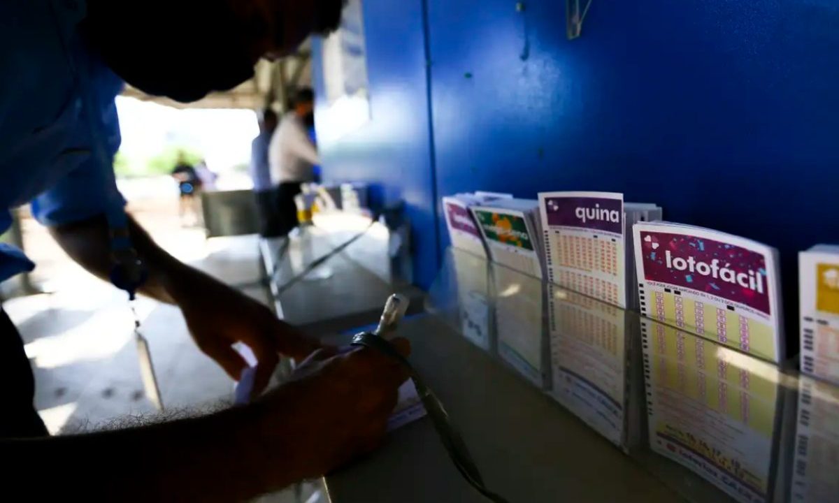 Foto de uma pessoa preenchendo uma cartela para tentar acertar os resultados da Lotofácil 3682