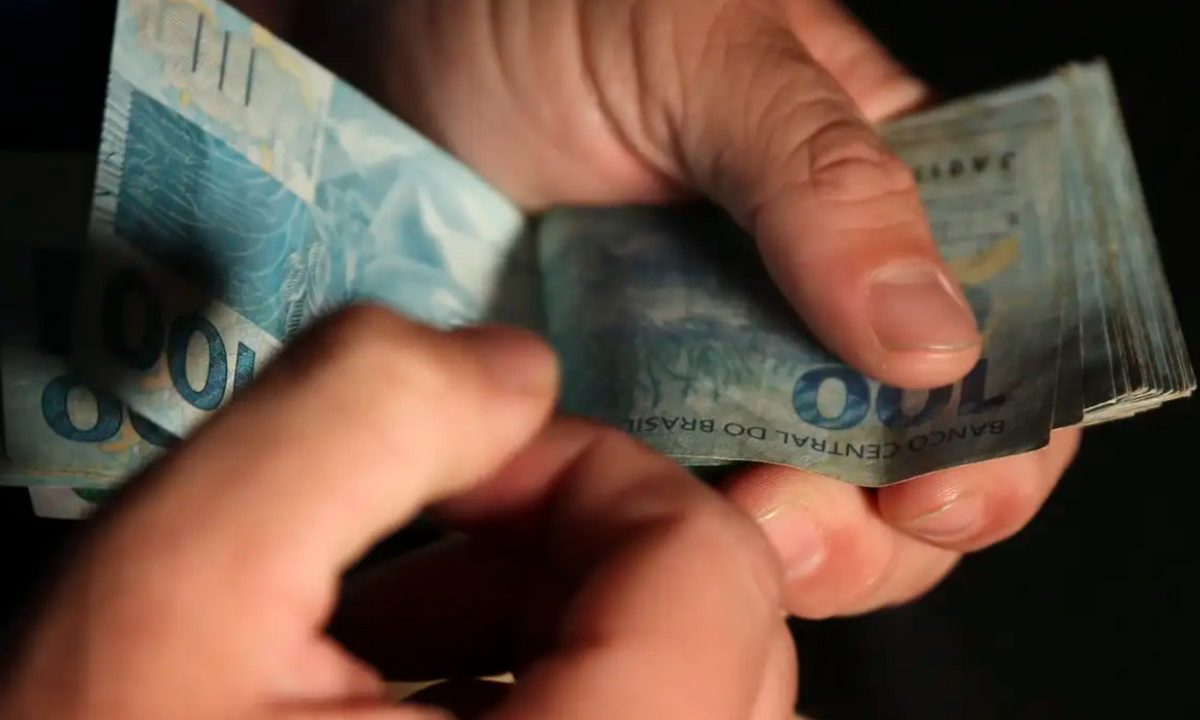 Foto de mão contando cédulas de R$100 para ilustrar o dinheiro que as apostas paranaenses vão receber no resultado da Mega-Sena 2987