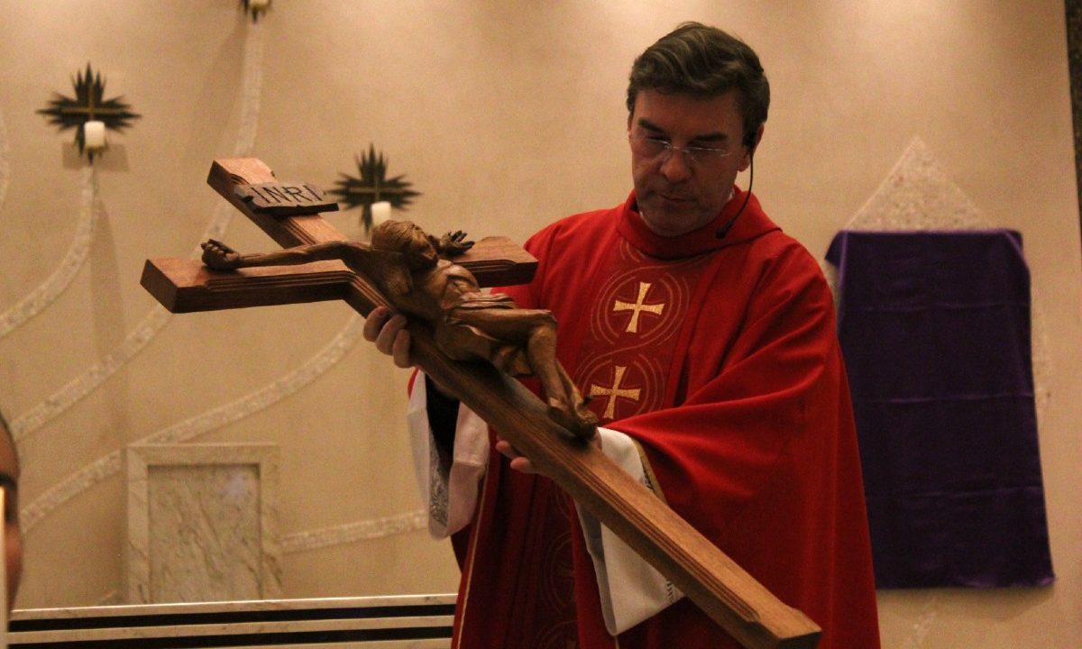 padre kleina com uma cruz para a programação da semana santa