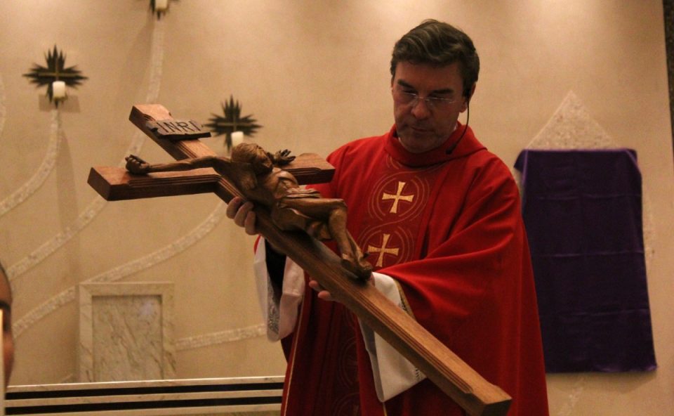 padre kleina com uma cruz para a programação da semana santa