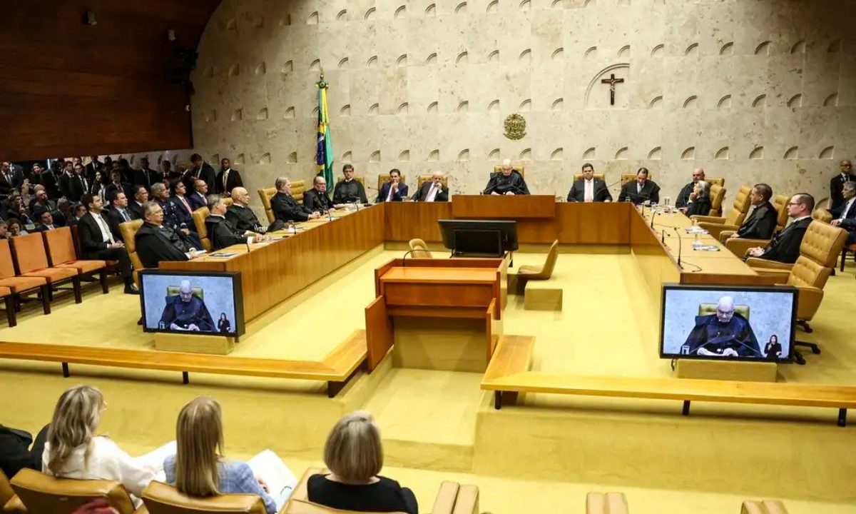 A imagem mostra ministros do STF sentados em suas cadeiras. Todos usando togas pretas. Ao fundo, uma parde em tons claros, assim como o chão.