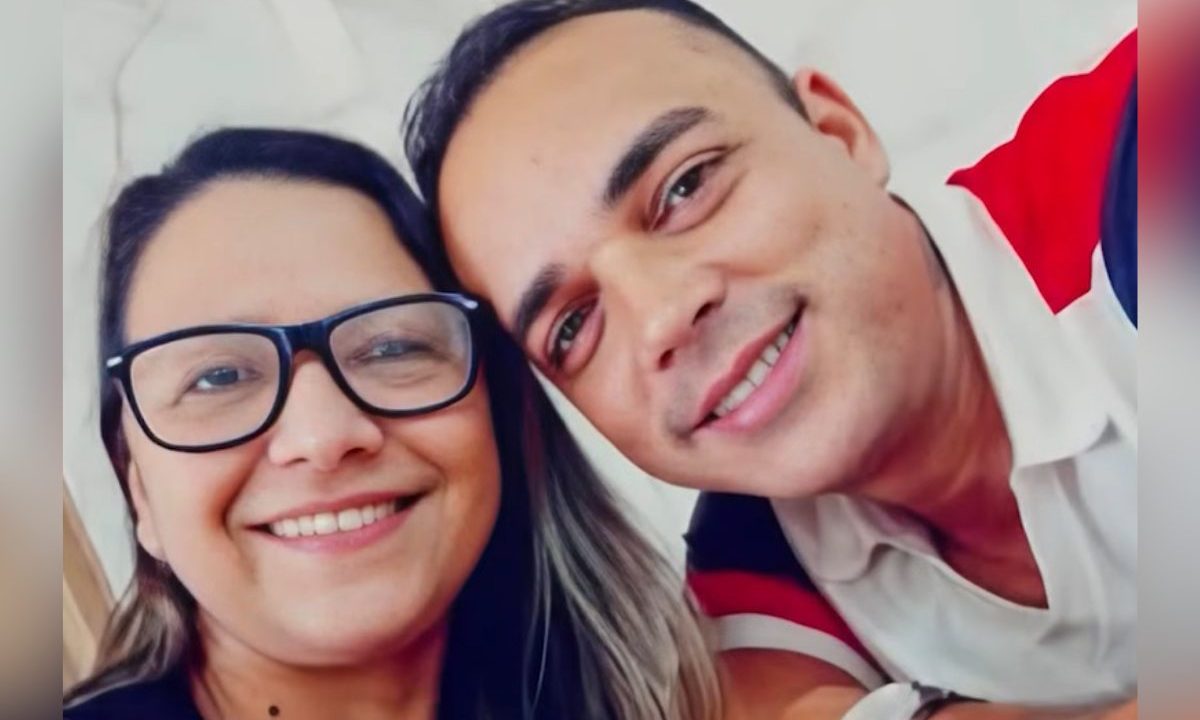 Imagem mostra o casal sorrindo para a foto. Ela usa óculos e tem cabelos longos. Ela usa camiseta preta. O suspeito de matar a companheira em Paranaguá usa camiseta branca e vermelha. Ele tem cabelo curto.