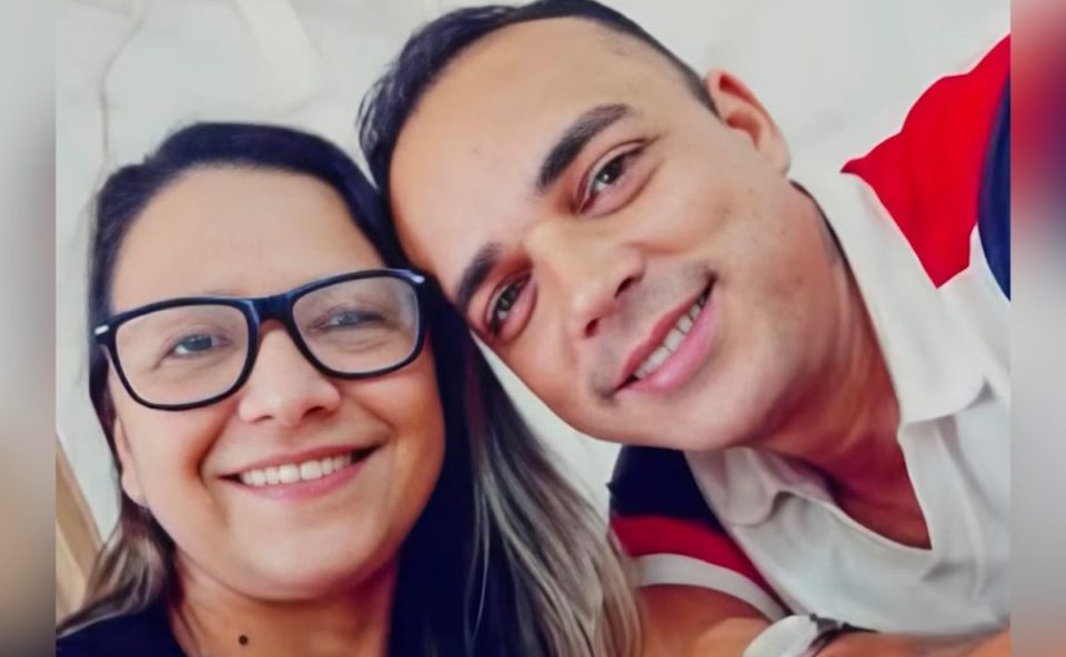 Imagem mostra o casal sorrindo para a foto. Ela usa óculos e tem cabelos longos. Ela usa camiseta preta. O suspeito de matar a companheira em Paranaguá usa camiseta branca e vermelha. Ele tem cabelo curto.