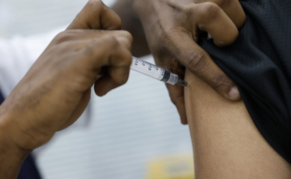 Foto ilustrativa mostra profissional da saúde apliucando vacina em braço de uma pessoa, em alusão ao caso do técnico de enfermagem preso por abusar de adolescente em Piraquara