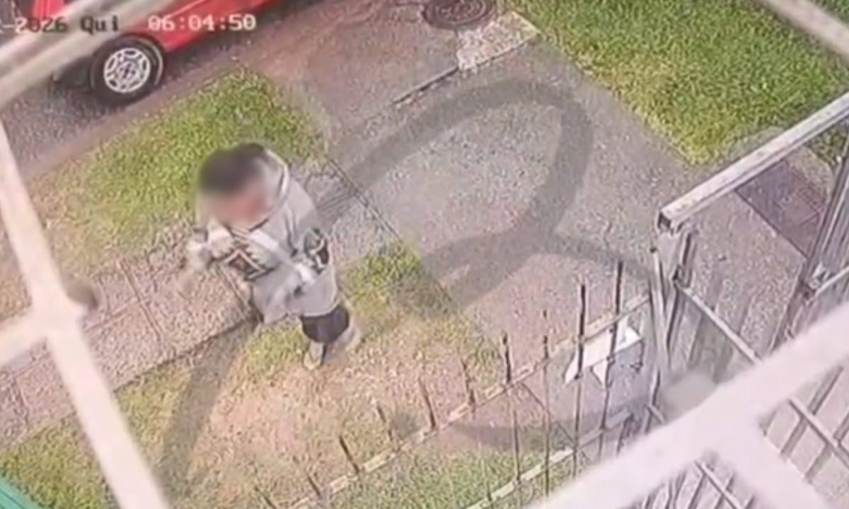 Vídeo mostra momento em que pai é executado em frente à creche. Imagem mostra esposa da vítima aos prantos na calçada, perto do veículo clio vermelho. Mulher usa uma blusa cinza.