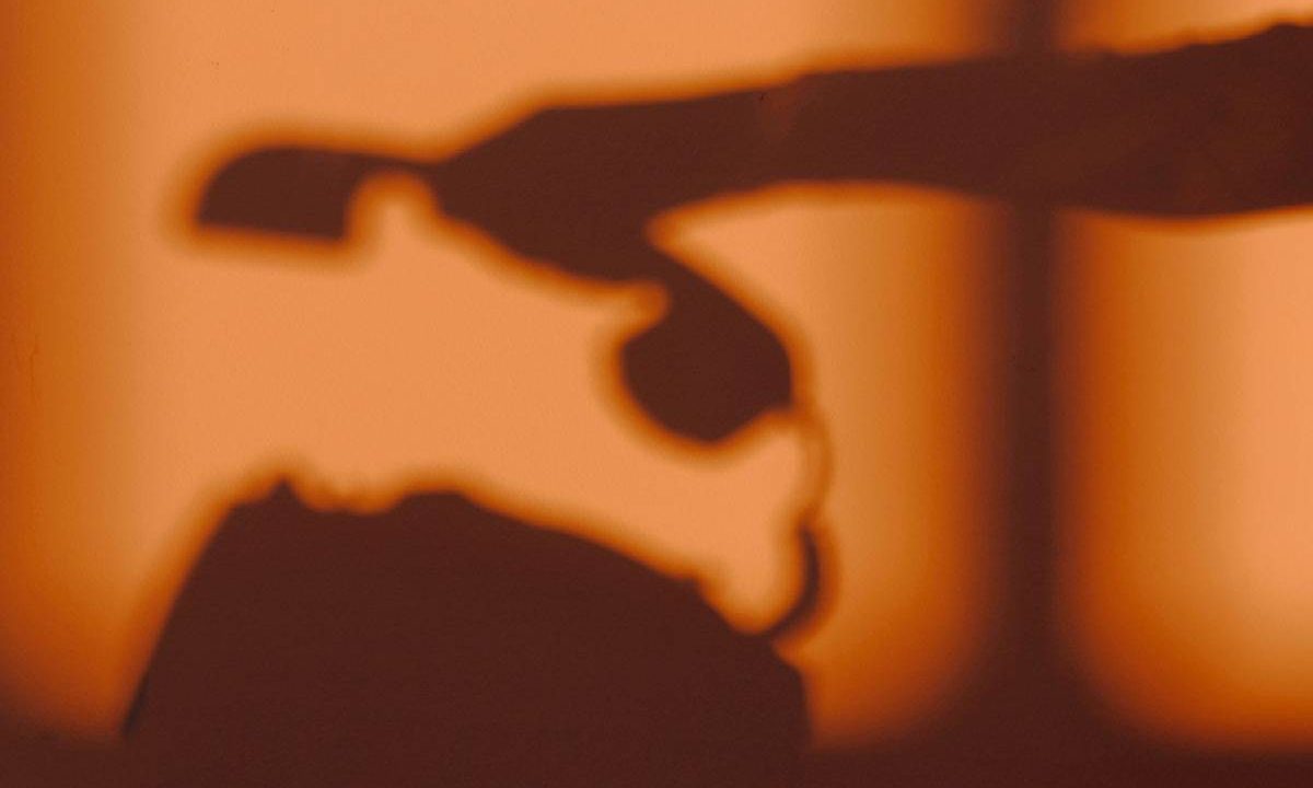 Foto mostra sombra de mão pegando o telefone