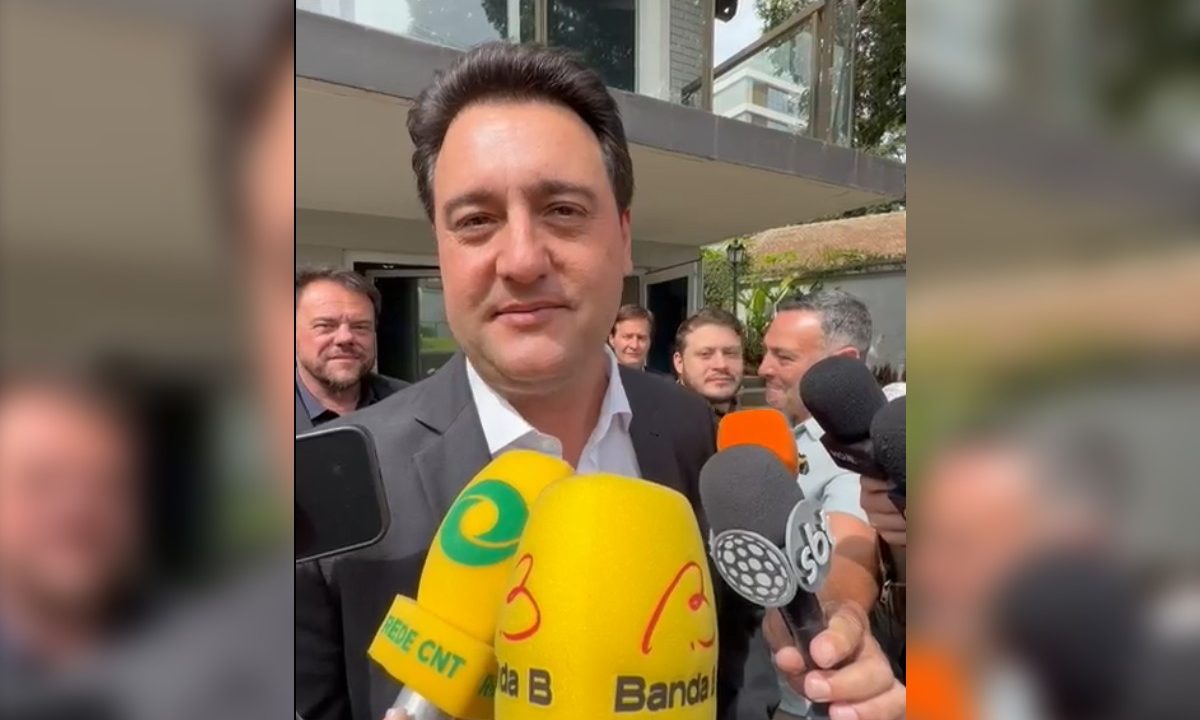 Cercado de microfones, governador Ratinho Junior dá entrevista a jornalistas na saída de um evento