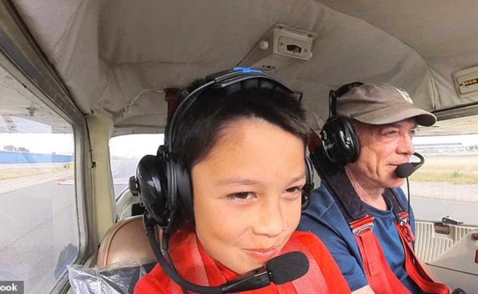 Menino usa fone de ouvido e está na cabine de piloto de um alvião, onde costuma pilotar