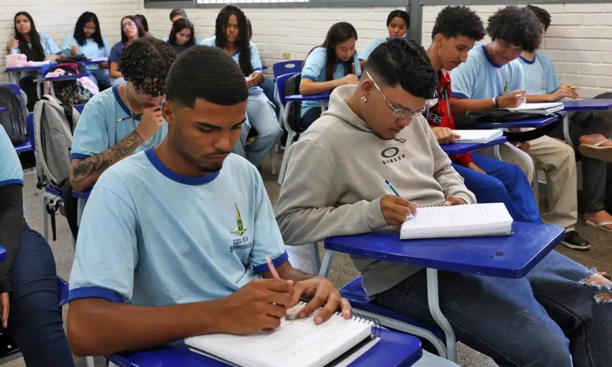 Estudantes em sala de aula, escrevendo em seus cadernos. Imagem ilustrativa para matéria sobre inscrições para vagas remanescentes do Fies