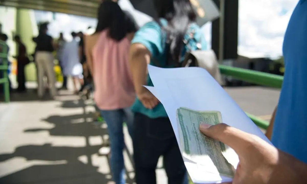 Foto de pessoa segurando documentos enquanto espera em uma fila; imagem usada para ilustrar matéria sobre a importância de jovens regularizar o seu voto até o dia 6 de maio