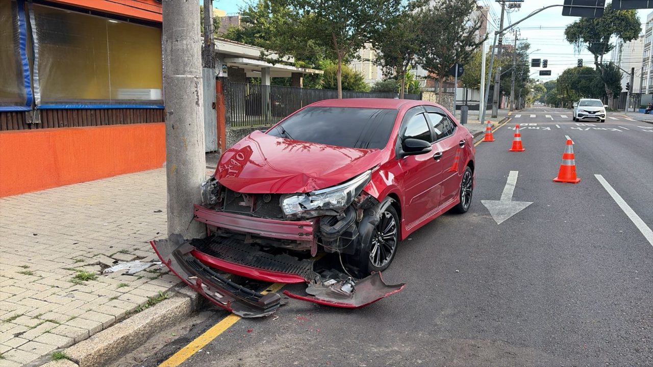 Carro vermelho bateu de frente com um poste. Dois motoristas brigaram após se envolverem em acidente no Alto da XV, em Curitiba. Um deles perdeu o controle do carro e bateu no poste