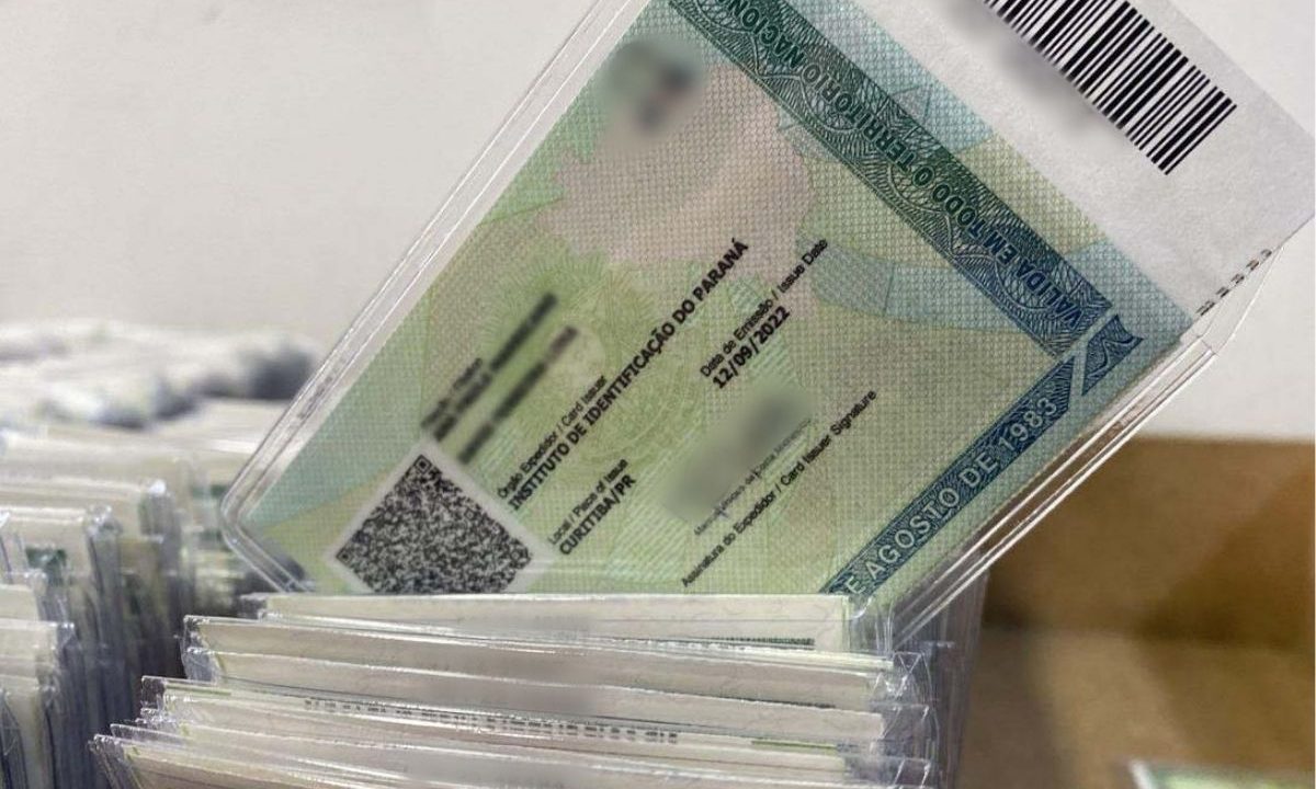 Imagem mostra uma carteira de identidade sendo tirado do meio de uma pilha de outras carteiras. Os dados pessoais estão borrados. A Carteira de Identidade Nacional (CIN), também conhecida como “novo RG”, pode ser solicitada pelo celular e entregue em casa
