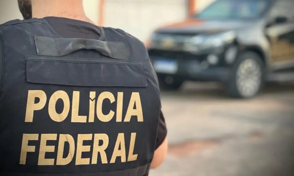 Foto mostra policial de costas para câmera, com o escrito "Polícia Federal" no colete à prova de balas, em alusão à operação que mira grupo envolvido com tráfico de drogas interestadual