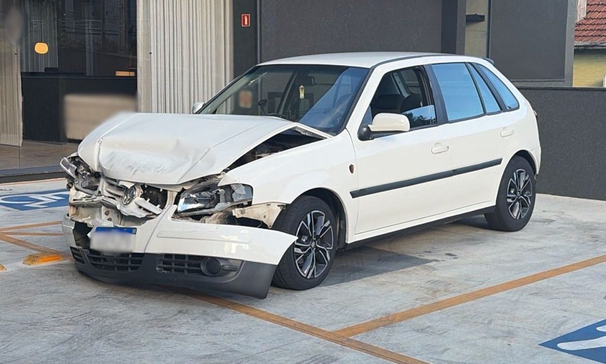 Parte da frente de um veículo branco danificada após acidente entre dois carros no bairro Ahú, em Curitiba.
