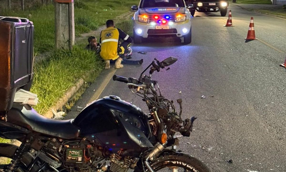 Motocicleta após acidente com viatura de resgate ao fundo em São José dos Pinhais