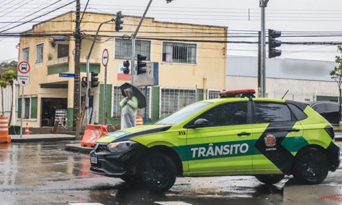 Imagem ilustrativa com agente de trânsito e viatura em bloqueio de rua, usada para representar alterações no trânsito durante o feriado de Páscoa em Curitiba.