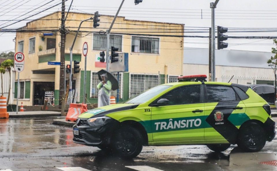 Imagem ilustrativa com agente de trânsito e viatura em bloqueio de rua, usada para representar alterações no trânsito durante o feriado de Páscoa em Curitiba.