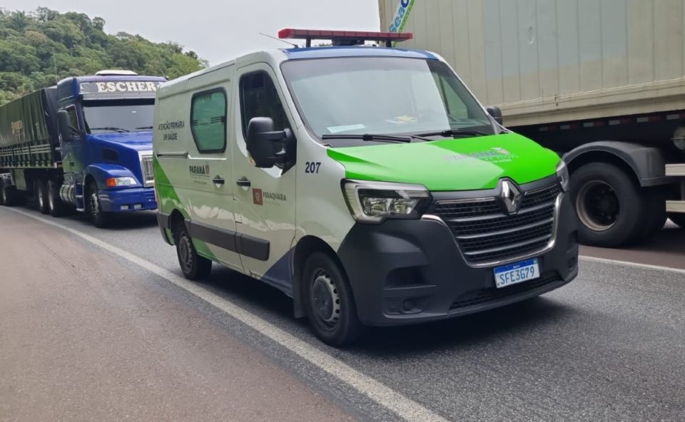 Foto mostra ambulância de Piraquara parada em fila causada por acidente entre dois caminhões na BR-277, em Morretes, no litoral do Paraná. Ambulância é branca e verde, com logotipos da Secretaria Estadual da Saúde. Atrás dela há um caminhão azul.