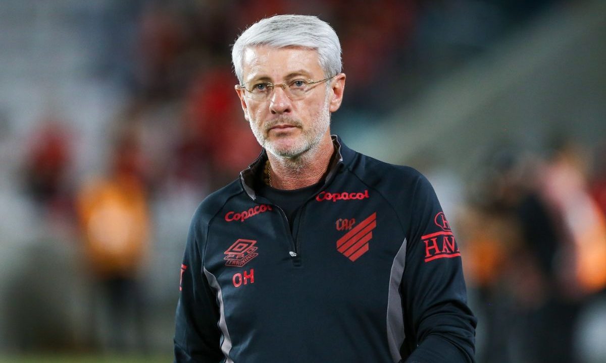 Odair Hellmann, técnico do Athletico, em pé à beira do campo durante partida, usando uniforme preto do clube, com expressão séria enquanto observa o jogo