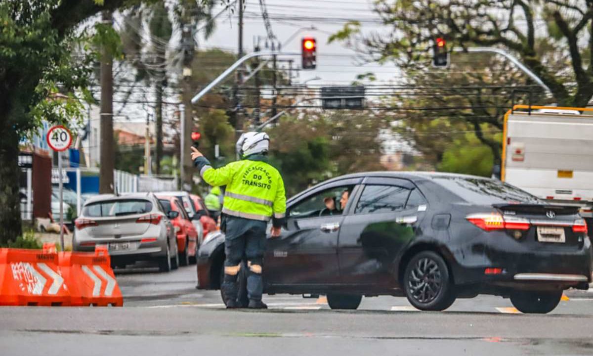 Agente orientando motorista em local com bloqueio de trânsito em Curitiba