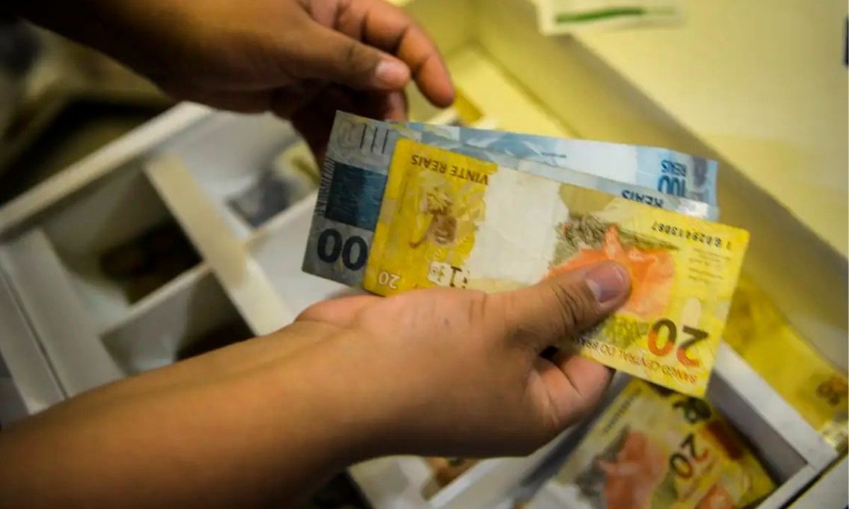 Carga tributária bate novo recorde no Brasil. A imagem mostra uma pessoa segurando dinheiro.