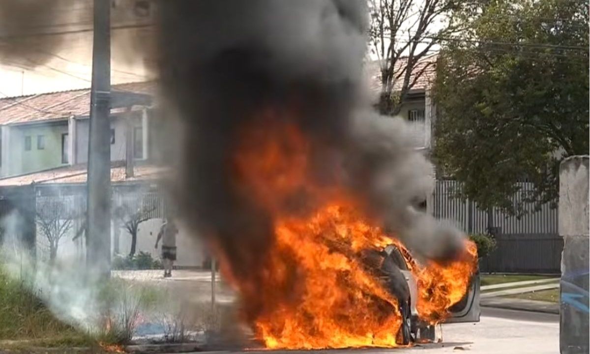 Carro elétrico pega fogo e interdita acesso à BR-277 no bairro Cajuru, em Curitiba. A imagem mostra o carro pegando fogo na entrada no bairro Cajuru.