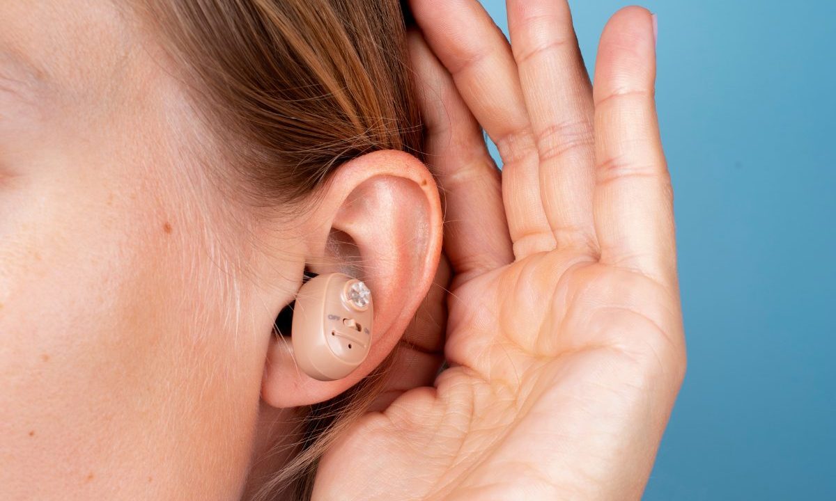 Mulher vista de perfil usando aparelho auditivo discreto atrás da orelha