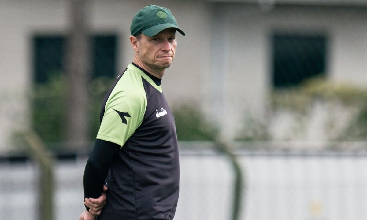 O técnico do Coritiba, Fernando Seabra, observa o treino com expressão séria, usando boné verde e uniforme do clube, em preparação da equipe