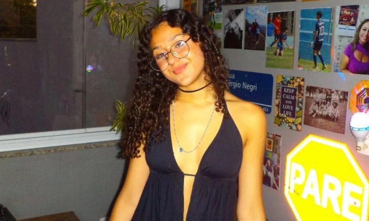 Foto mostra a adolescente Melissa Felippe Martins Santos, de 17 anos, sorrindo para foto em um quarto com pôsteres atrás dela. Ela usa óculos de grau, tem cabelos cacheados e sorri levemente. Ela estava desaparecida e seu corpo foi encontrado em uma área de mata.