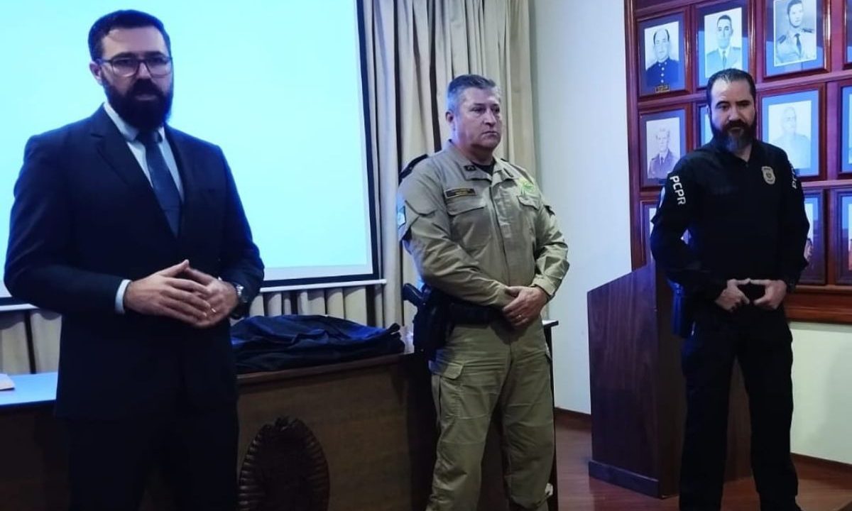 Policiais parados em pé com as mãos em frente ao corpo