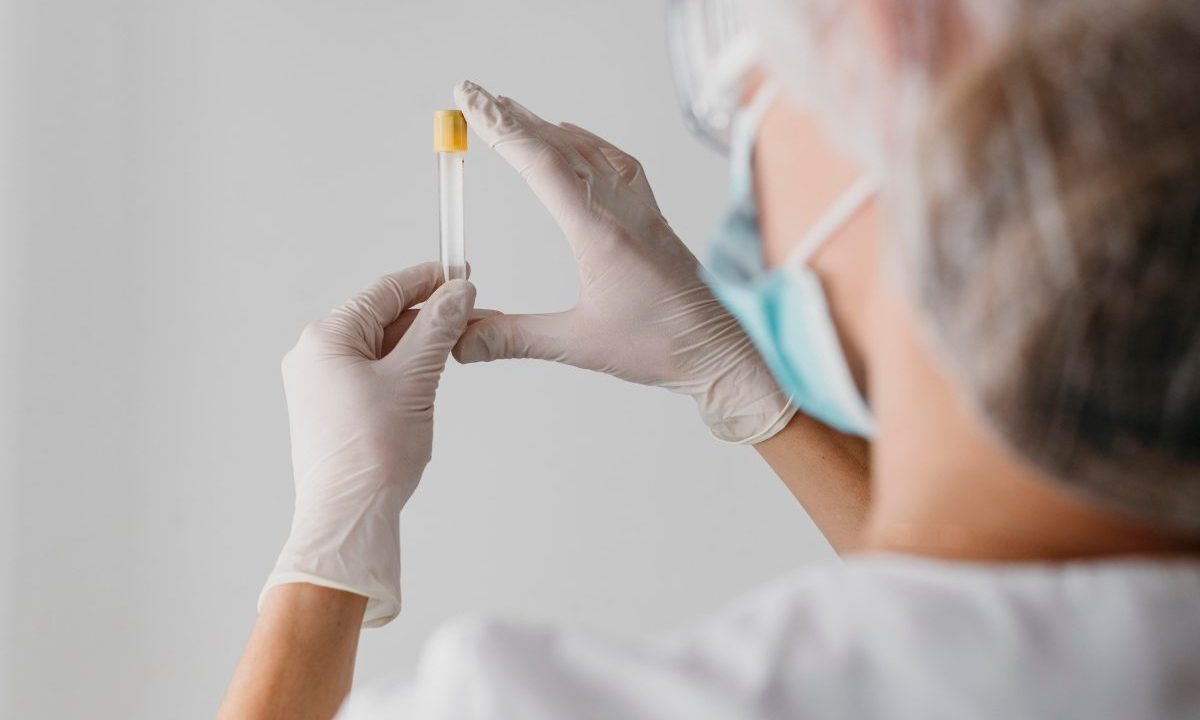 Profissional de saúde com luvas segura tubo de ensaio com amostra em laboratório para exame genético de câncer