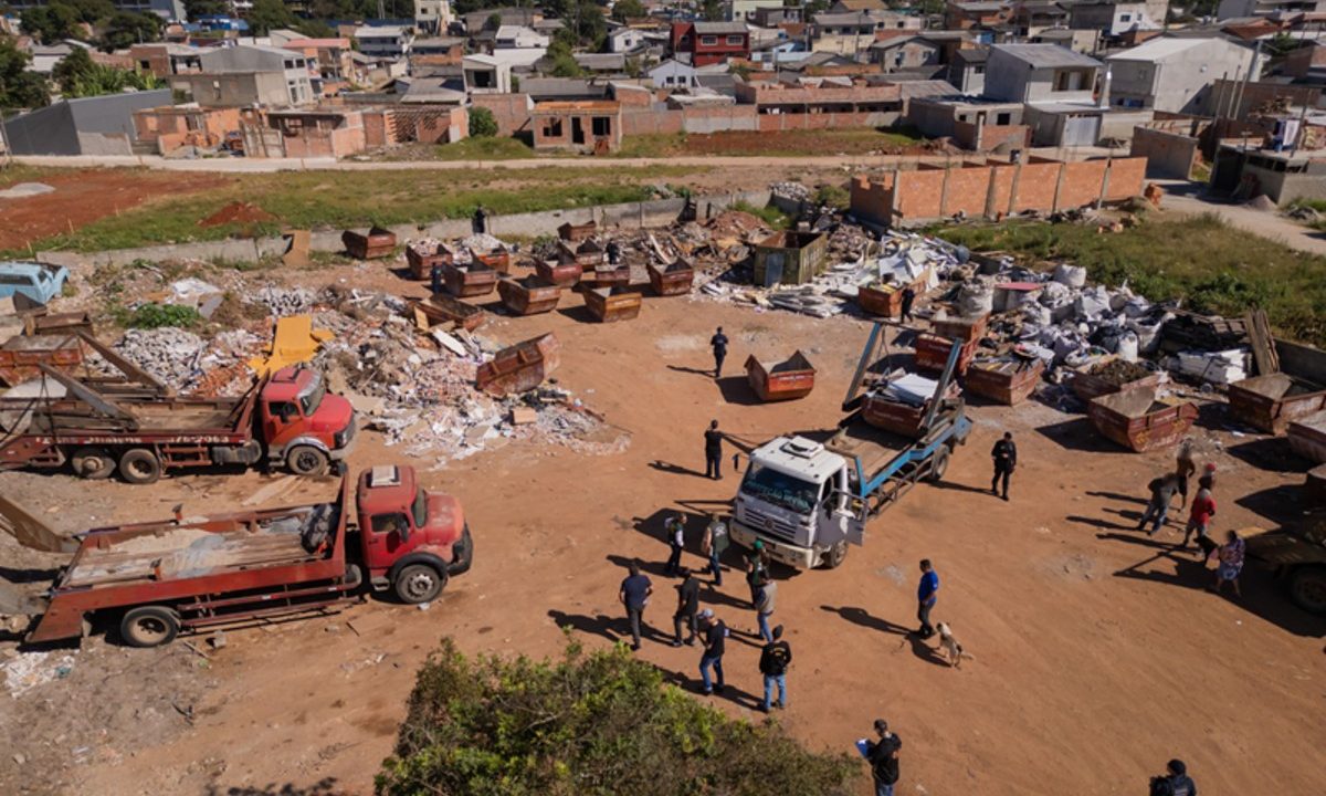 Vista aérea de um terreno amplo no bairro Alto Boqueirão, em Curitiba, onde ocorre uma operação de fiscalização contra crimes ambientais.