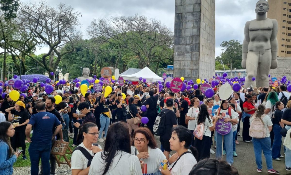 Foto mostra professores da rede municipal de ensino de Curitiba se reunindo na Praça 19 de Dezembro, no Centro, diante da greve considerada ilegal pela Justiça. Eles seguram no alto balões roxos e amarelos.