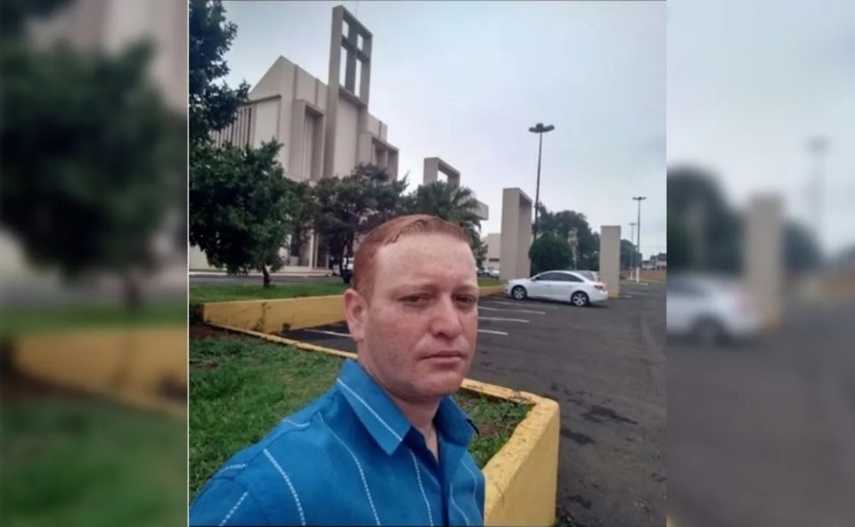 Na foto, Bruno Alfredo dos Santos, de 37 anos, homem que foi morto a tesouradas no Paraná, posa para selfie em frente a uma igreja católica. Ele usa uma camisa azul, com listras brancas