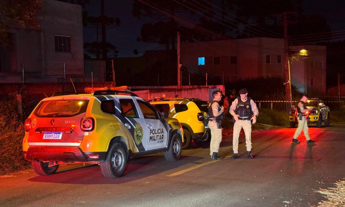 Foto tirada à noite mostra três policiais militares ao lado de viatura em área onde homem foi morto com facada no pescoço em Colombo