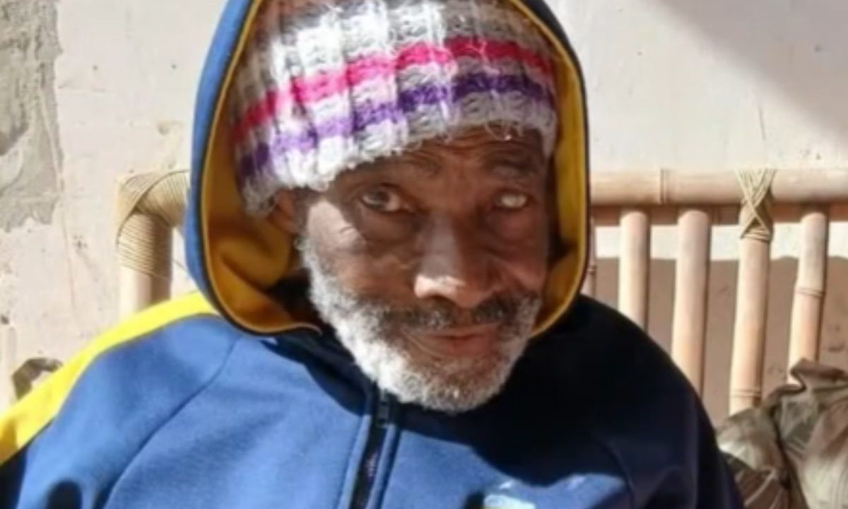 O idoso com Alzheimer que está desaparecido em Matinhos aparece na foto com uma blusa azul marinho e amarela e touca. Ele é um homem negro, com barba branca.