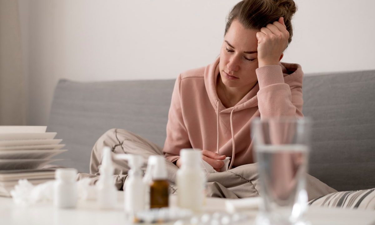 Mulher com sintomas de gripe e cansaço em casa, ilustrando imunidade baixa