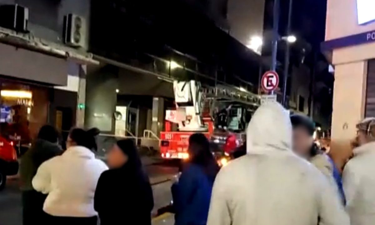 Moradores observam atuação de bombeiros durante incêndio em prédio no centro de Buenos Aires à noite