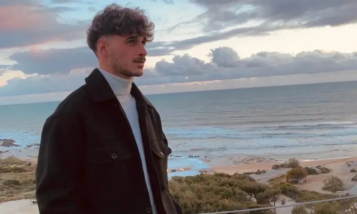 O jogador de futebol Gabriele Vaccaro foi assassinado por um adolescente que queria roubar pizzas. Imagem mostra Gabriele com blusa preta e cabelo liso. Ele tem barba e bigode. A foto foi tirada em uma praia.